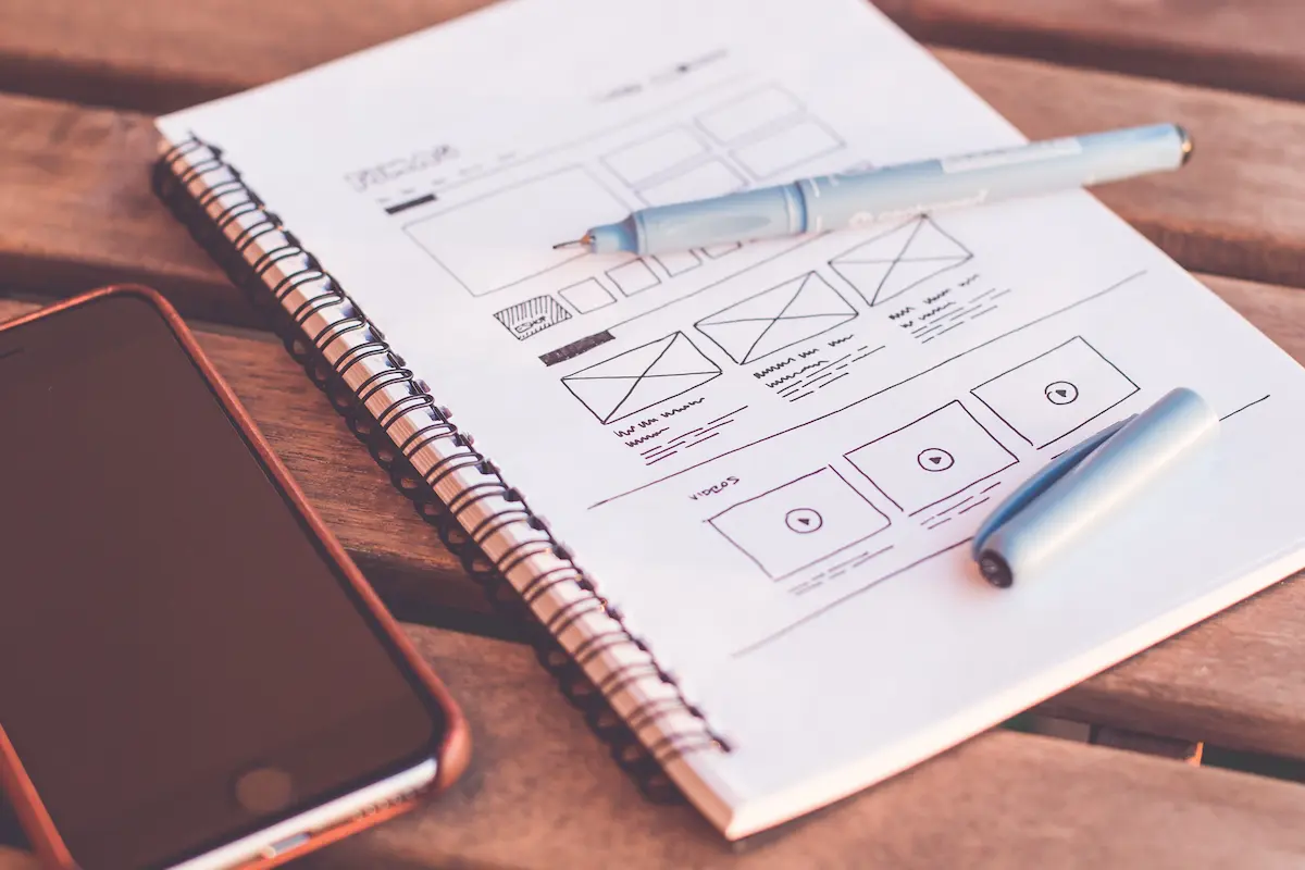 Pen resting on a spiral notebook next to a mobile phone